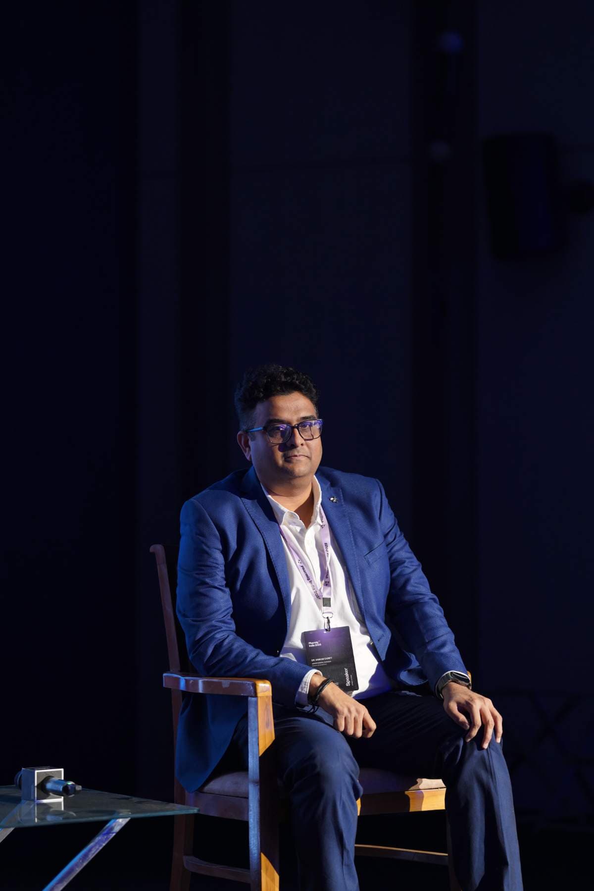 A speaker seated on stage during a fireside conversation at Pharmig India 2025