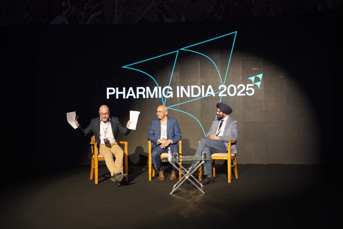 Three panellists in discussion on stage beneath the Pharmig India 2025 logo