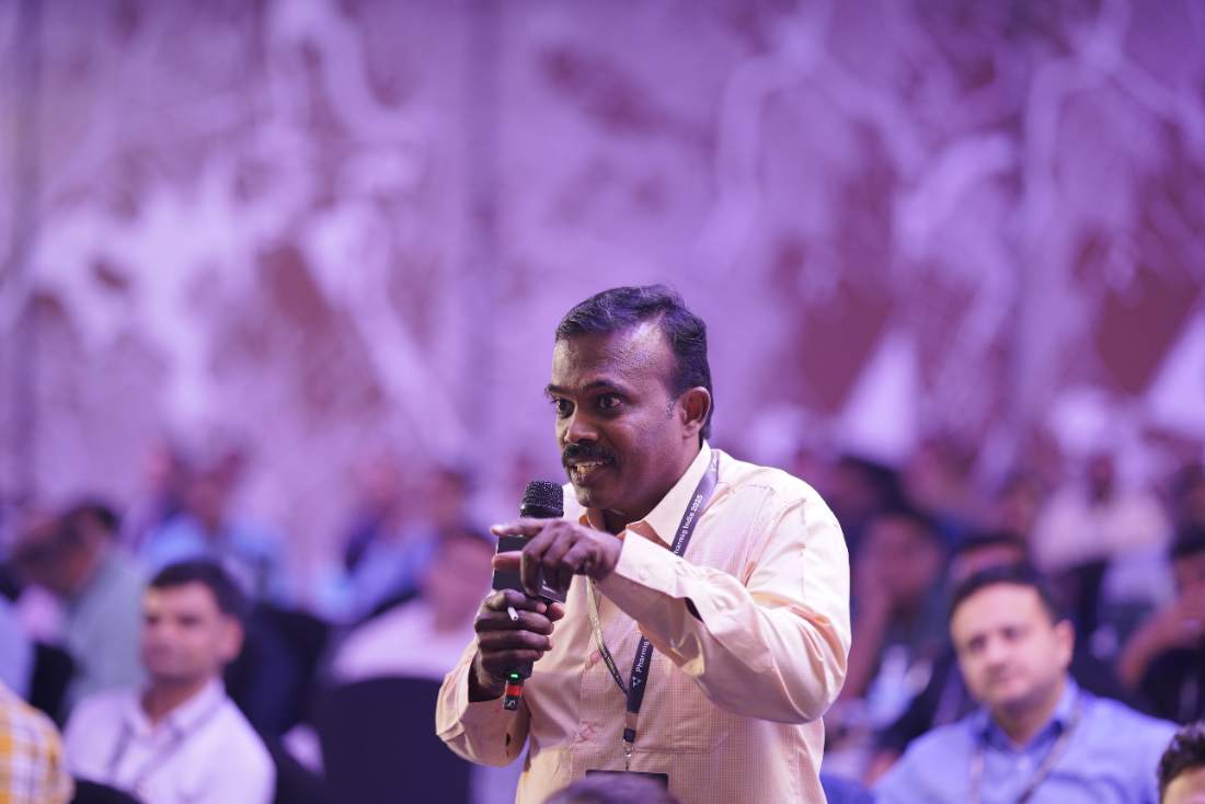 A delegate asking a question into a handheld microphone during a Pharmig India 2025 session