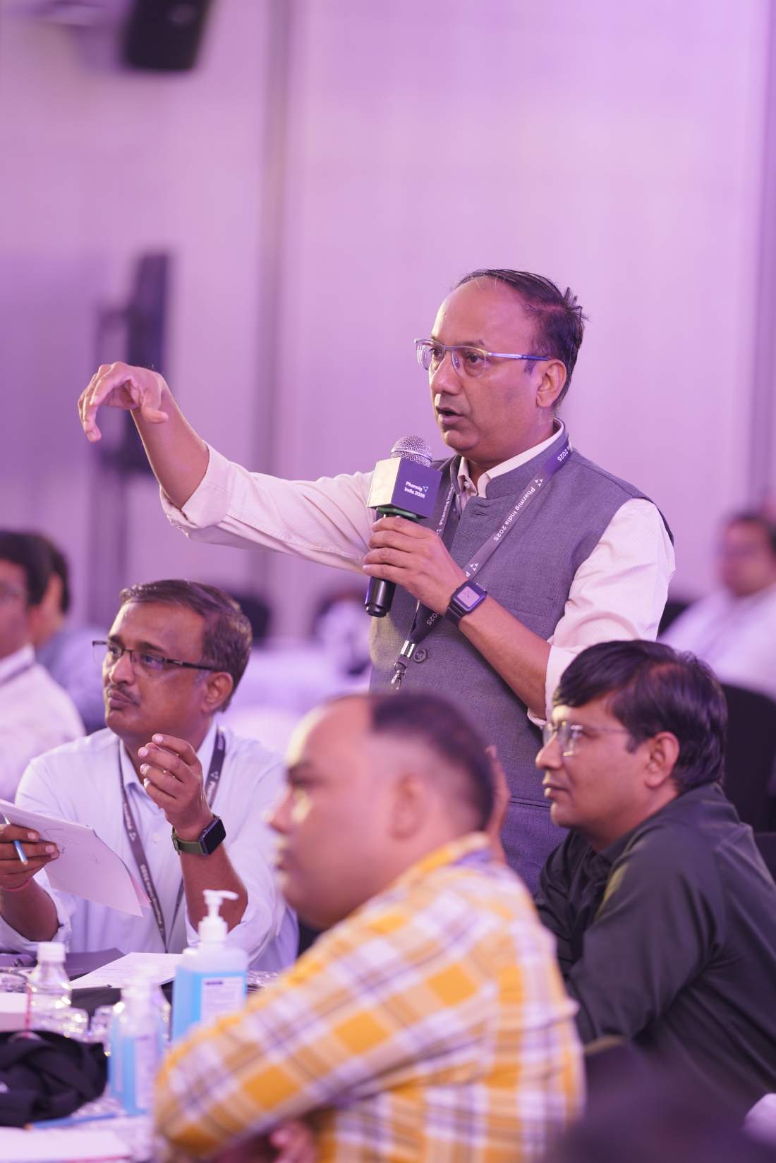 A delegate gesturing as he puts a question to the panel, seated colleagues around him